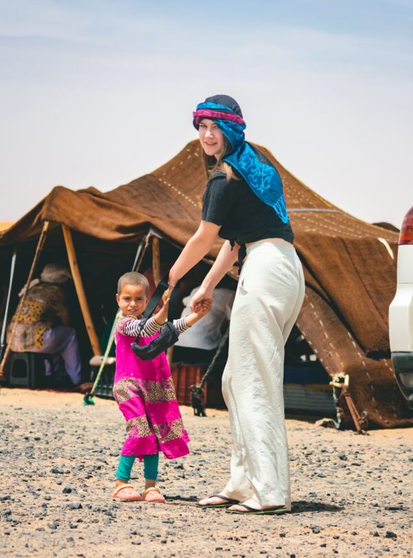 Smiling woman and child holding hands in a Moroccan desert camp. 2 Days Tour from Marrakech To Zagora ,morocco travel