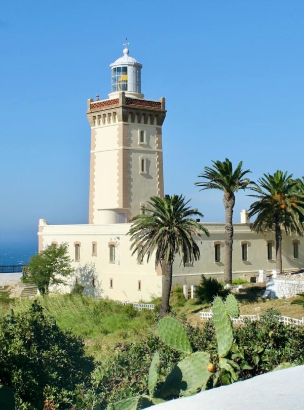 A scenic view of Cape Spartel Lighthouse surrounded by lush palm trees on a sunny day in Morocco travel 5 Days desert tour from Marrakech