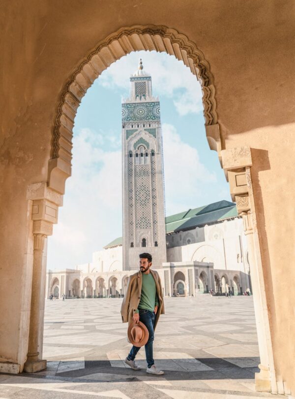 Man walking through archway with Hassan II Mosque minaret in Casablanca, Morocco travel , 8 Days Tour From Casablanca