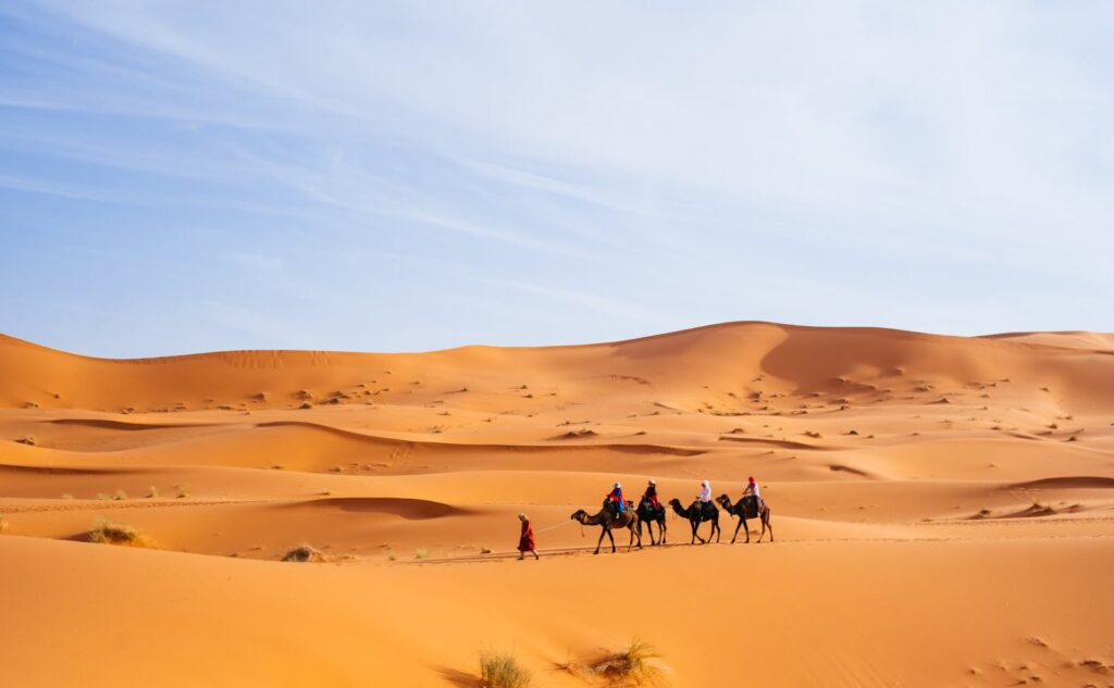 Tourists riding camels across the dunes of Merzouga, Morocco, a popular Sahara destination.Morocco travel Best 7-Day Morocco Trip from Marrakech