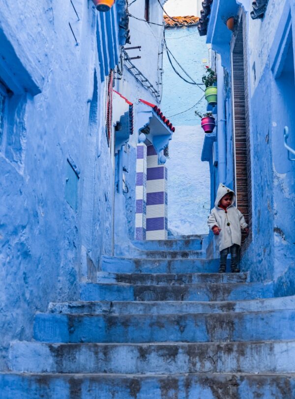 a person standing on a set of stairs in a narrow alleyway morocco travel 5 Days desert tour from Marrakech