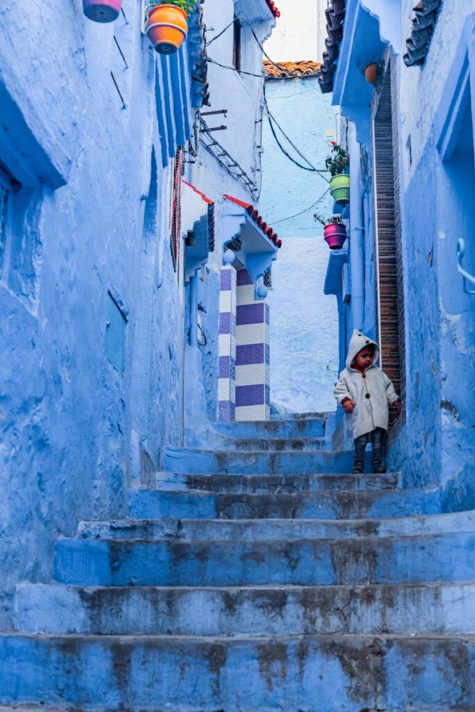 a person standing on a set of stairs in a narrow alleyway morocco travel 5 Days desert tour from Marrakech